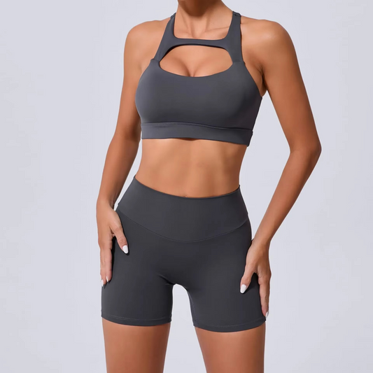Person wearing a gray sports bra and shorts set on a light gray background