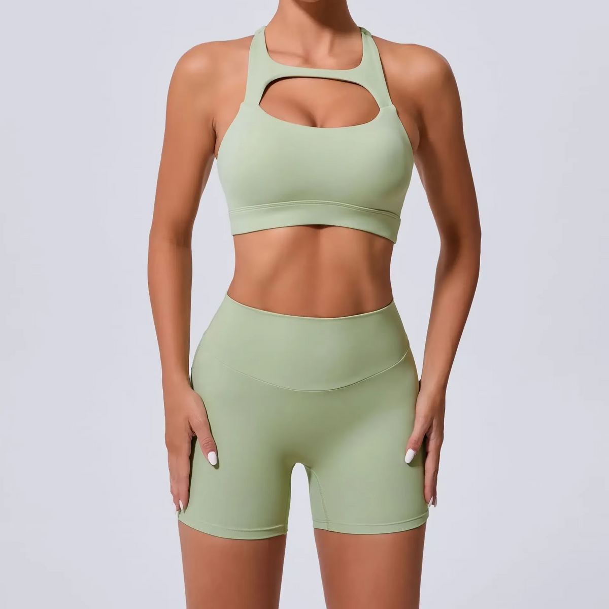 Person wearing a green sports bra and shorts set on a light gray background