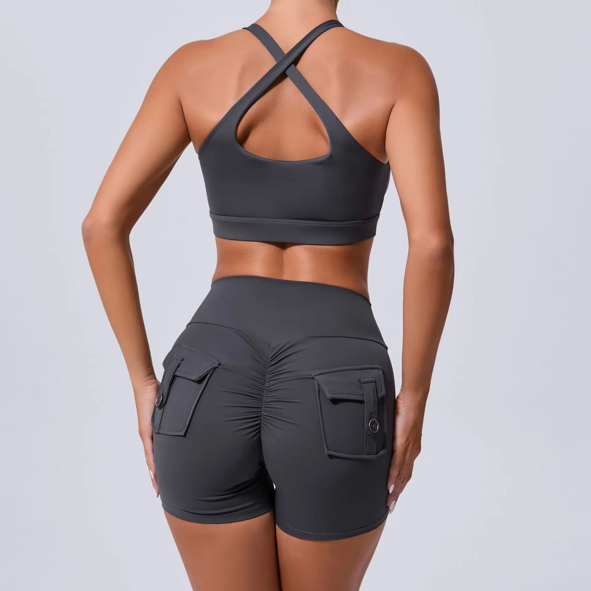 Person wearing a black sports bra and shorts set on a light gray background