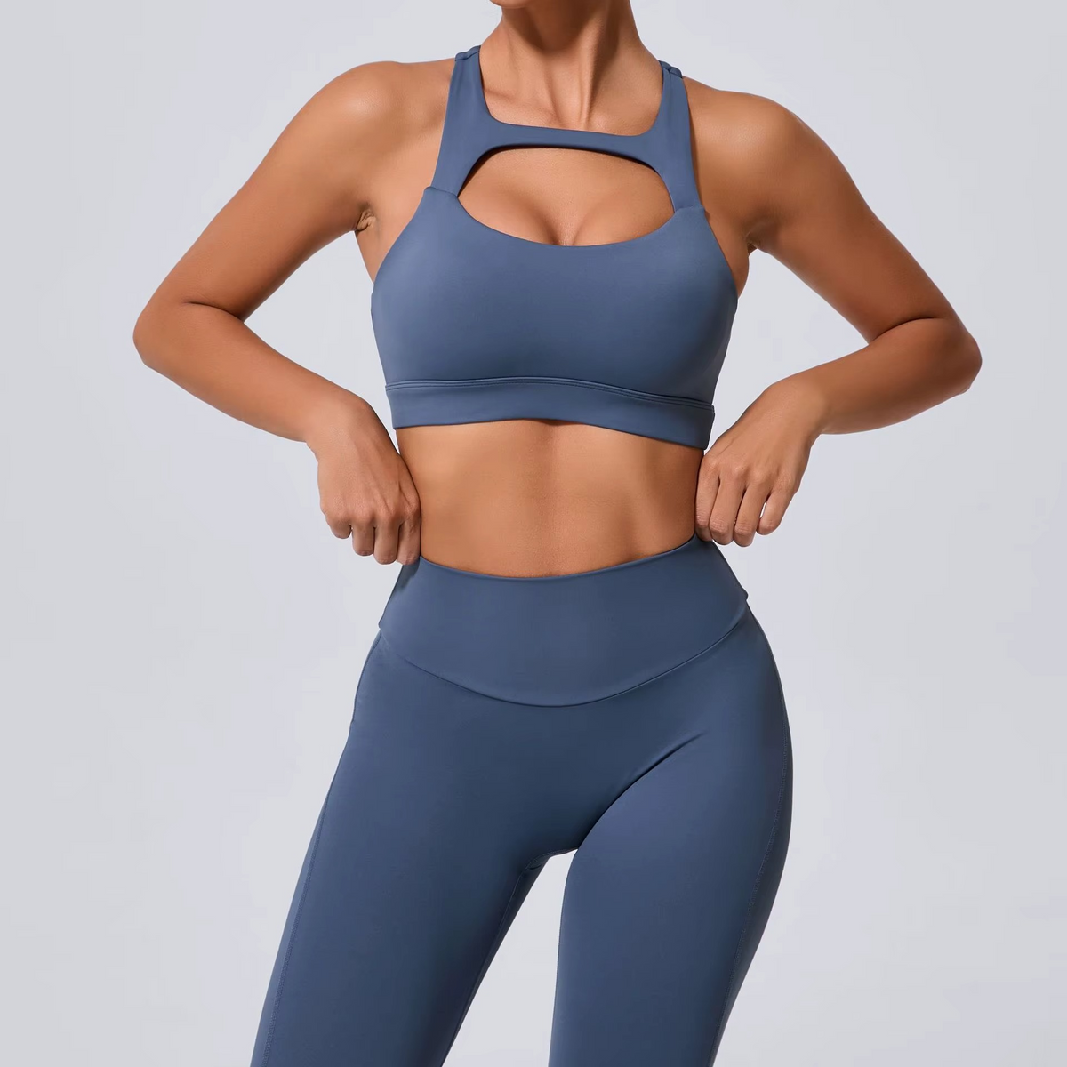 Person wearing a blue sports bra and leggings on a light gray background